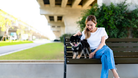 Happy young asian woman playing and sitting on a bench in the park with her dog. Pet lover conceptの写真素材