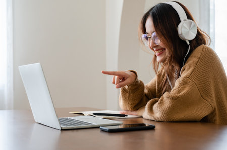 Young asian woman wearing glasses and headset working on computer laptop at house. Work at home, Video conference, Video call, Student learning online classの写真素材