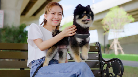 Happy young asian woman playing and sitting on a bench in the park with her dog. Pet lover conceptの写真素材
