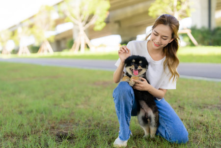 Happy young asian woman playing and sitting on grass in the park with her dog. Pet lover conceptの写真素材