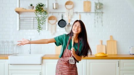 Asian young woman dancing in kitchen room. Female happy and relaxing at free time on weekendの写真素材