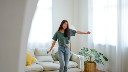 Young asian woman dancing on the floor in living room at home. Happy asia female smile relaxing in house, healthy mental wellness and wellbeingの写真素材