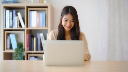 Young asian woman working at home. Female using computer laptop on desk at houseの写真素材
