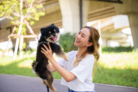 Happy young asian woman playing and sitting on road in the park with her dog. Pet lover conceptの写真素材