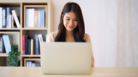 Young asian woman working at home. Female using computer laptop on desk at houseの写真素材