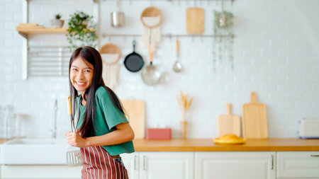 Asian young woman dancing in kitchen room. Female happy and relaxing at free time on weekendの写真素材