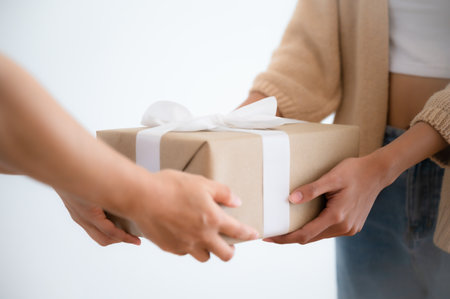 Close up image of Asian woman hands holding a gift wrapped with white ribbon. Young woman gives a gift in a box. Happy new year, Merry christmas, Thanksgivingの写真素材