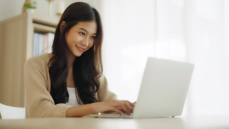 Young asian woman working at home. Female using computer laptop on desk at houseの写真素材