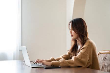 Young asian woman working at home. Female using computer laptop on desk at houseの写真素材