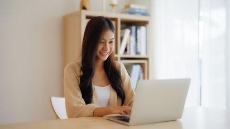 Young asian woman working at home. Female using computer laptop on desk at houseの写真素材