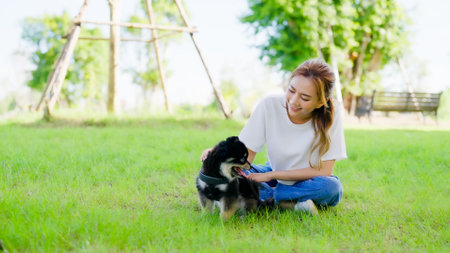 Happy young asian woman playing and sitting on grass in the park with her dog. Pet lover conceptの写真素材
