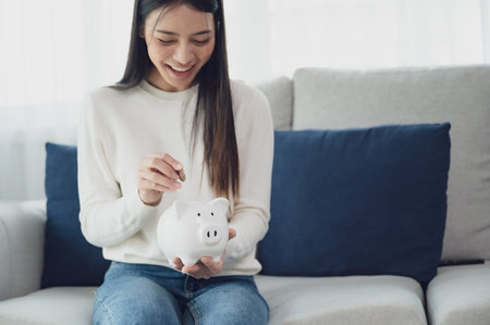 Asian woman putting coin in piggy bank. Save money and investment conceptの写真素材