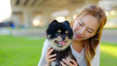Happy young asian woman playing and sitting on grass in the park with her dog. Pet lover conceptの写真素材