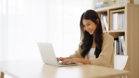 Young asian woman working at home. Female using computer laptop on desk at houseの写真素材