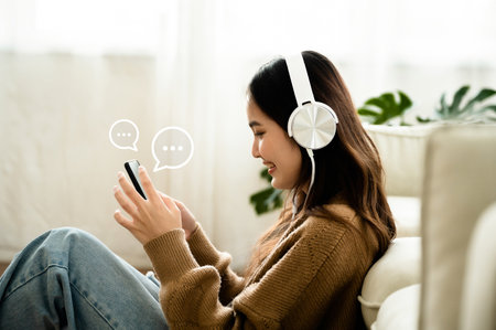 Young asian woman using mobile smartphone in living room. Online live chat chatting on application communication digital media website and social networkの写真素材