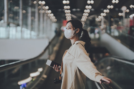 Young asian woman passenger in airport terminal or modern train station. Asia woman commuter travels with luggage on escalatorの写真素材