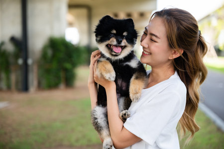 Happy young asian woman playing and sitting on road in the park with her dog. Pet lover conceptの写真素材
