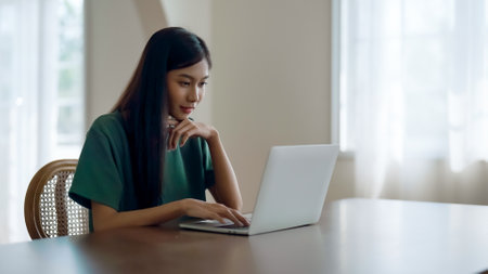 Young asian woman working at home. Female using computer laptop on desk at houseの写真素材