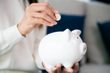 Asian woman putting coin in piggy bank. Save money and investment conceptの写真素材