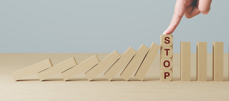 Hand stopping wooden domino business crisis effect or risk protection conceptの写真素材