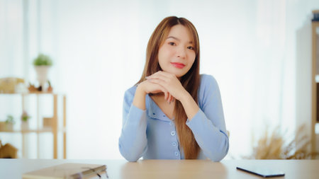Happy young asian woman blogger applicant teacher sit at home office look at camera doing online job interview during video chat conference call record vlog teaching on webinar meetingの写真素材