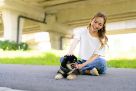 Happy young asian woman playing and sitting on road in the park with her dog. Pet lover conceptの写真素材
