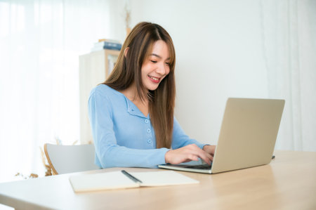 Young asian woman working at home. Female using computer laptop on desk at houseの写真素材