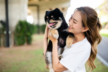 Happy young asian woman playing and sitting on road in the park with her dog. Pet lover conceptの写真素材