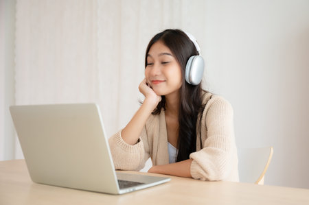 Young asian woman wearing headset while working on computer laptop at house. Work at home, Video conference, Video call, Student learning online classの写真素材