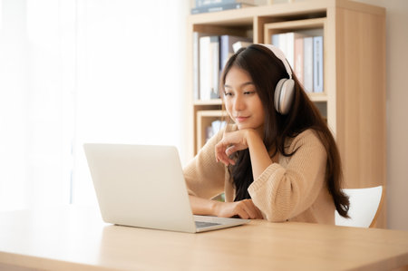 Young asian woman wearing headset while working on computer laptop at house. Work at home, Video conference, Video call, Student learning online classの写真素材