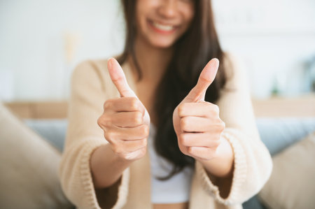 Happy teen asian girl blogger smiling face waving hand talking to webcam recording vlog, social media influencer streaming, making video call at home. She thumb up good or betterの写真素材