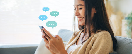 Young asian woman using mobile smartphone. Chatting conversation in chat box icons pop up bubble speech. Social media direct messageの写真素材