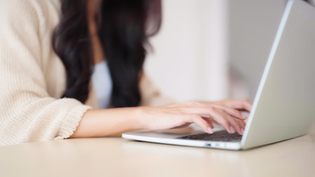 Hand of asian woman typing on computer laptop keyboard at houseの写真素材