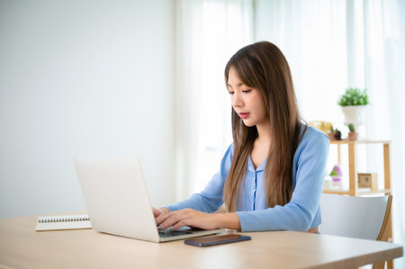 Young asian woman working at home. Female using computer laptop on desk at houseの写真素材