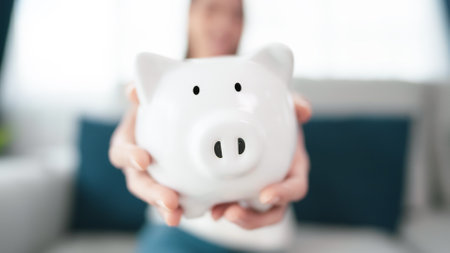 Young asian woman holding white piggy bank at home. Save money and investment conceptの写真素材