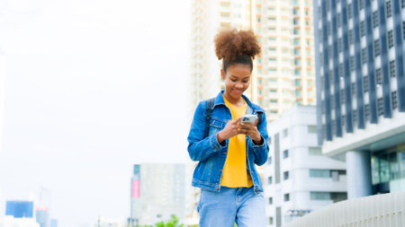 Black young woman, using smart phone and smile with walking in the city outdoor. Happy african student, young female walking with mobile by a buildingの写真素材