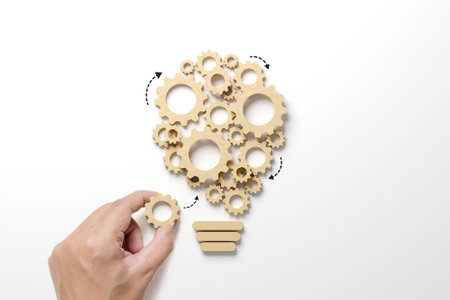 Business process and workflow automation with flowchart. Hand holding wooden cog flowing process management lightbulb shape on white backgroundの写真素材