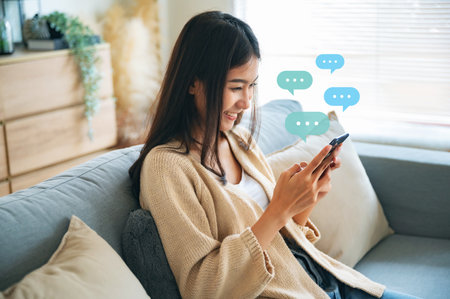 Young asian woman using mobile smartphone. Chatting conversation in chat box icons pop up bubble speech. Social media direct messageの写真素材