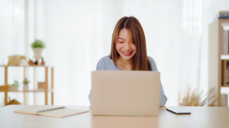 Young asian woman working at home. Happy female using computer laptop on desk at houseの写真素材