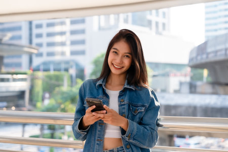 Young asian woman walking and using smartphone on the streetの写真素材