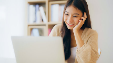 Young asian woman working at home. Happy female using computer laptop on desk at houseの写真素材