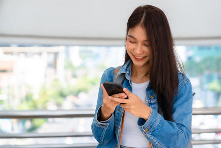 Young asian woman walking and using smartphone on the streetの写真素材