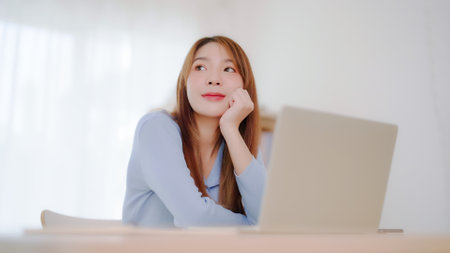 Young asian woman working at home. Happy female using computer laptop on desk at houseの写真素材