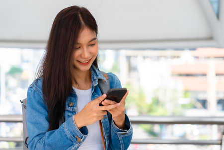 Young asian woman standing and using smartphone on the streetの写真素材