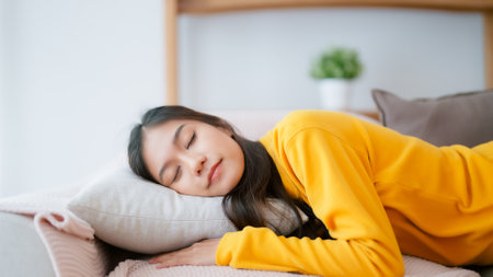 Asian woman resting at home on couch, feeling exhausted after work, lacking energy, or overworked, too tired, and lacking motivationの写真素材
