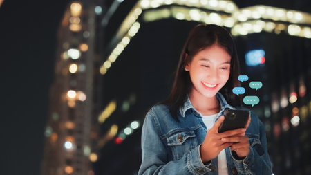 Hand of woman typing text on mobile smartphone in city night life. Online live chat chatting on application communication digital media website and social networkの写真素材