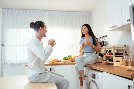 Romantic young couple drinking coffee together in the kitchen, having a great time together in a morningの写真素材