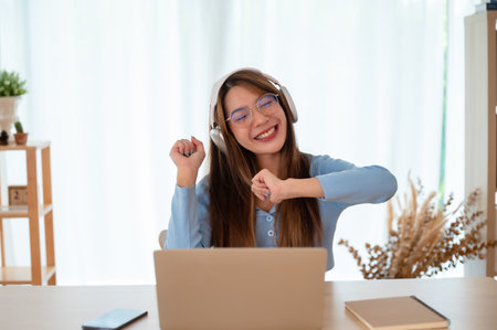 Funny euphoric young asian woman celebrating winning or getting ecommerce shopping offer on computer laptop. Excited happy girl winner looking at laptop celebrating successの写真素材