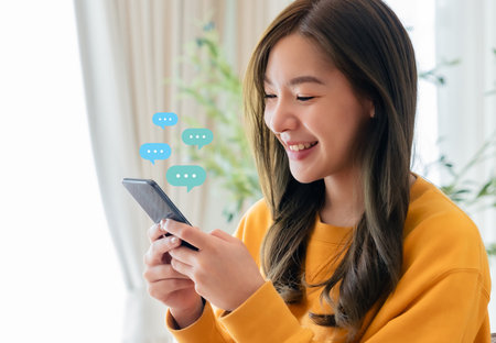Adorable young Asian woman using mobile smartphone. Online live chat chatting on application communication digital media website and social networkの写真素材