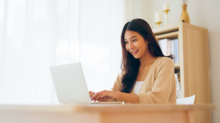 Funny euphoric young asian woman celebrating winning or getting ecommerce shopping offer on computer laptop. Excited happy girl winner looking at notebook celebrating successの写真素材